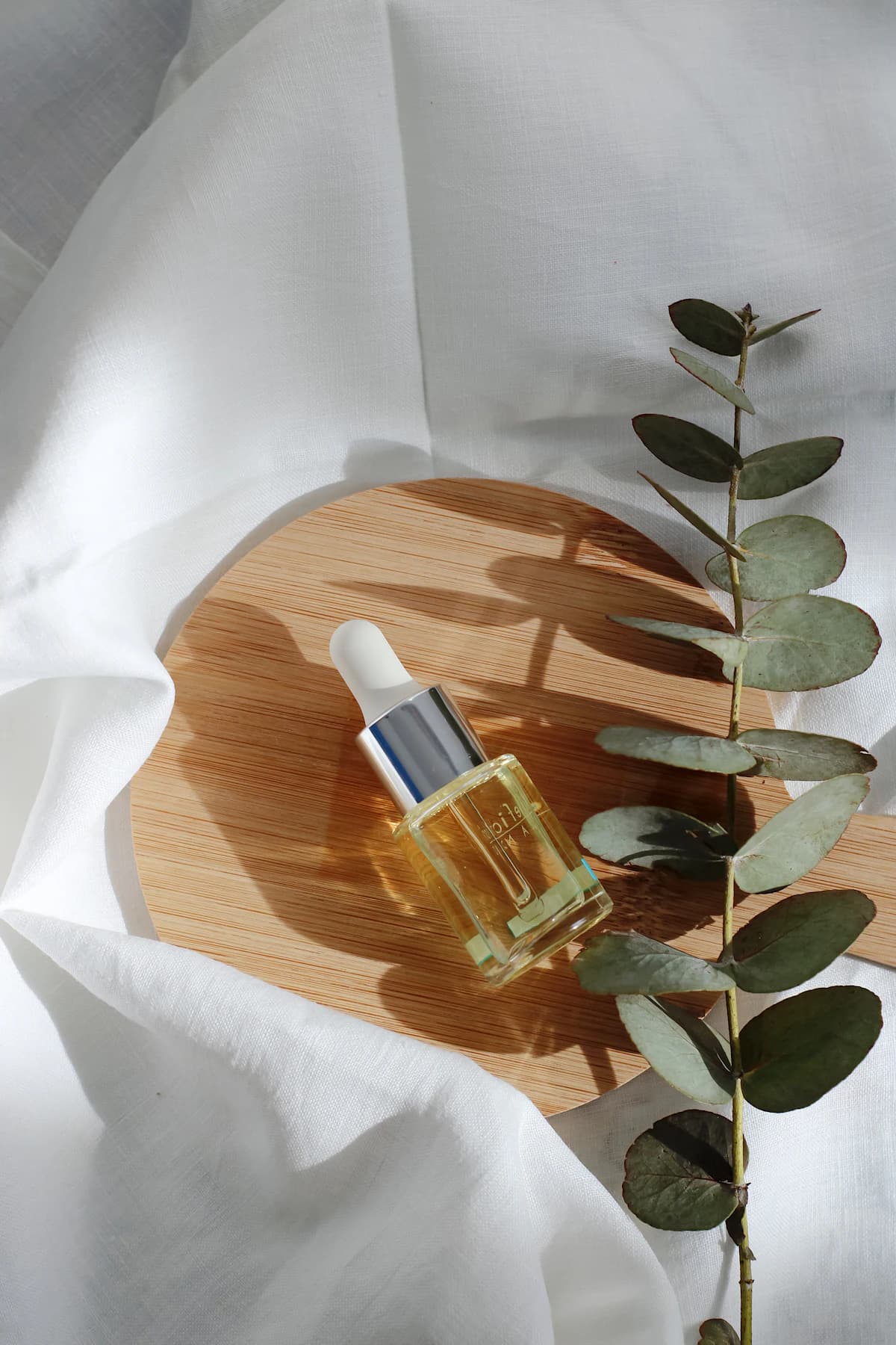 Vrouw past kalmerende serum aan op rustige huid na microneedling-behandeling in een lichte badkamer